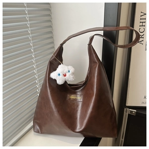 Detail of dark brown faux leather tote bag with star plush charm and rectangular label