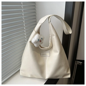 Detail of off-white tote bag with FASHION & BAGS patch and plush cloud charm