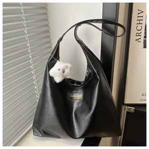 Detail of black faux leather shoulder bag with star charm and golden fashion tag
