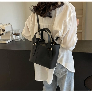 Dettaglio della borsa tote nera opaca con anelli dorati e tracolla regolabile per donna