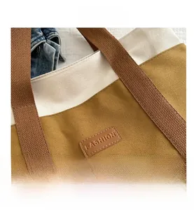 Détail de couture contrastée et écusson en cuir FASHION sur un grand sac en toile