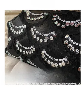 Detail shot of black lace bag featuring silver sequin embroidery and delicate mesh texture