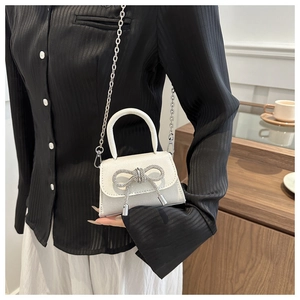 Détail du mini sac blanc avec nœud en strass et décoration de pompon argenté