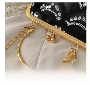 Detail of black lace evening bag with gold floral handle and silver sequins