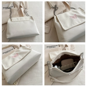 Detail view of white shoulder bag with pink butterfly embroidery and metal chain strap