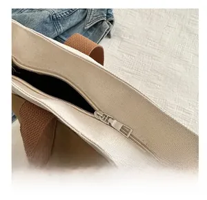 Détail de la fermeture éclair en métal argenté sur un sac cabas en toile bicolore