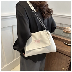 Detail of pink butterfly embroidery on a white crossbody bag with silver chain strap
