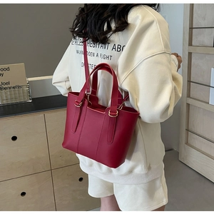 Dettaglio della borsa tote in pelle bordeaux con fibbie dorate indossata dalla modella
