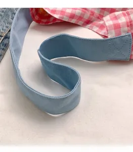Détail de la couture croisée sur la poignée large d'un sac cabas à motif à carreaux