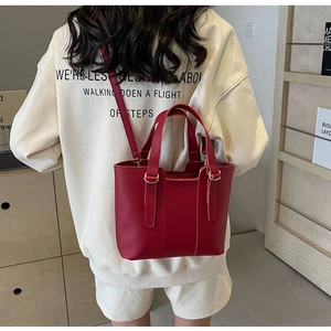 Dettaglio borsa tote in pelle rosso scuro con finiture dorate e tracolla regolabile