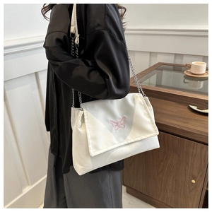 Close-up of white crossbody bag with pink butterfly embroidery and silver chain strap