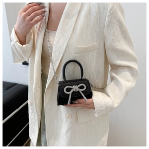 Détail du mini sac à paillettes noires avec noeud strass et chaîne argentée sur modèle