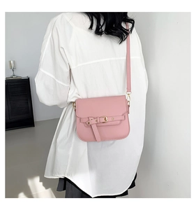 Detailansicht der rosa Satteltasche mit goldener Schnalle am Modell im weißen Hemd