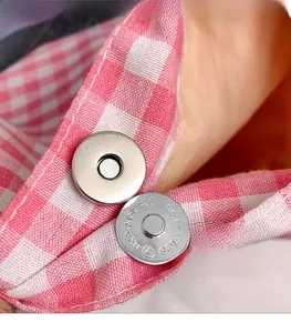 Détail du fermoir magnétique argenté sur un sac cabas tissé à carreaux roses et blancs