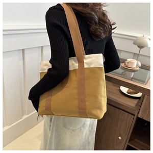 Vue arrière d'un grand sac cabas en toile jaune porté à l'épaule dans un café chaleureux