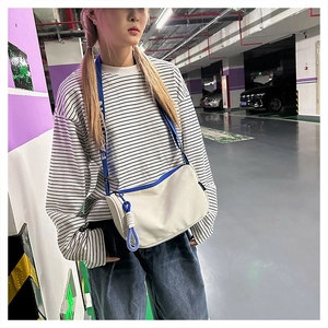 Détail du sac bandoulière en toile blanche avec sangle bleue FASHION et nœud décoratif