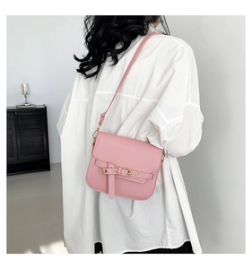Lifestyle-Foto einer rosa Satteltasche mit goldener Schnalle, als Umhängetasche getragen
