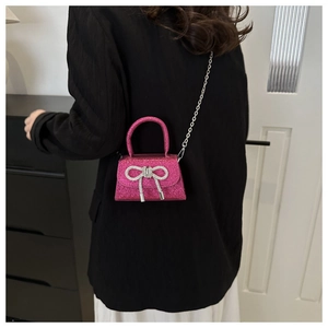 Mini sac bandoulière rose à paillettes avec nœud en strass sur un mannequin
