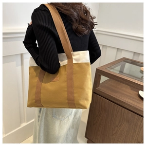 Détail du sac cabas en toile avec panneaux contrastés jaune et blanc sur un modèle