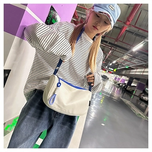 Sac à bandoulière en toile beige et bleu présenté dans un cadre de vie décontracté