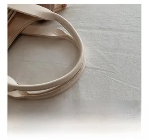 Detailed close-up of cream leather crescent bag handle with precise stitching work