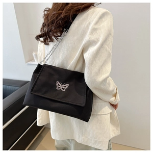 Detail of elegant black canvas shoulder bag with silver chain and butterfly embroidery