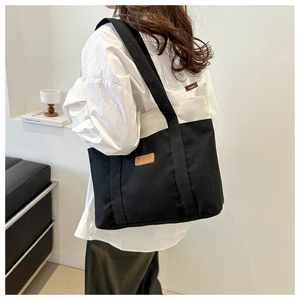 Détail du sac cabas en toile bicolore noir et blanc avec étiquette de mode en cuir