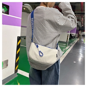 Sac bandoulière en toile blanche avec sangle bleue à logo et détail de fermeture éclair