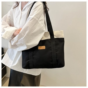 Détail du sac cabas minimaliste en toile noir et blanc avec étiquette mode en cuir