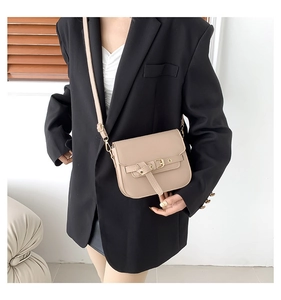 Beige Satteltasche mit goldener Schnalle, getragen über einem schwarzen Blazer-Look