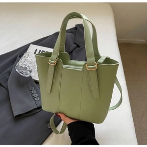 Dettaglio di una borsa tote in pelle verde pallido con inserti oro e chiusura a zip