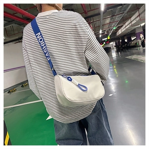 Gros plan d'un sac bandoulière blanc avec sangle bleue Fashion sur le dos d'un mannequin