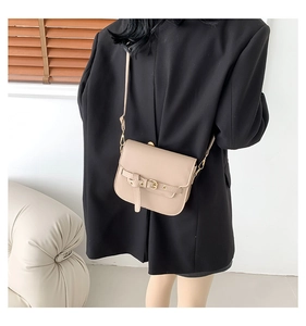 Detail einer Retro-Satteltasche in Beige mit Gürtelschnalle an einem Frauenmodell