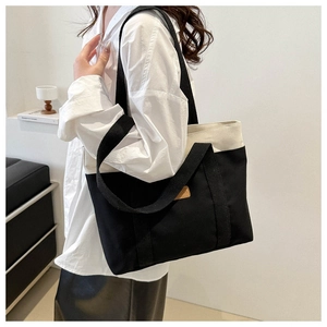 Détail d'un sac cabas en toile bicolore avec doubles anses et écusson en cuir élégant
