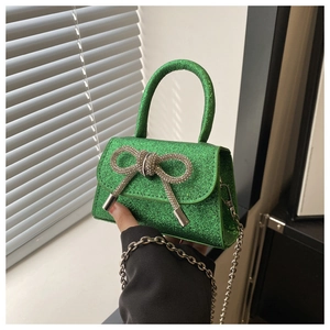 Détail du mini sac vert fluo à paillettes avec nœud en strass et bandoulière chaîne