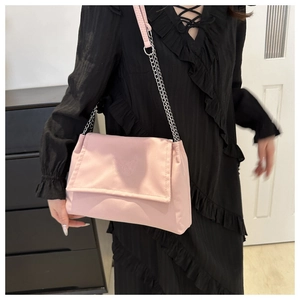 Detail of light pink shoulder bag featuring butterfly embroidery and silver chain strap