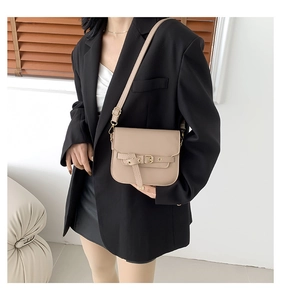 Detailansicht einer beigen Satteltasche mit Gürtelschnalle, getragen von einem Modell