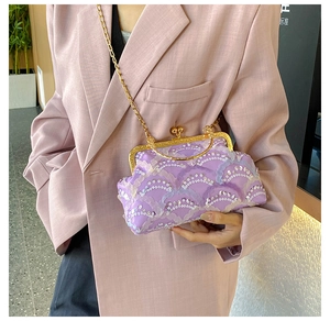 Detailed view of purple sequin evening bag with gold clasp held by a model