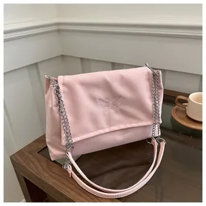 Detailed close-up of embroidered butterfly on pink fabric shoulder bag with silver chain