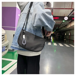 Détail du sac bandoulière noir en croissant avec pendentif tissé et sangle jacquard