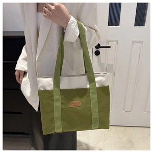 Détail du sac cabas en toile vert olive avec étiquette mode en cuir et poignée robuste