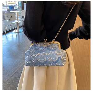 Lace evening bag with gold chain strap shown from side view on woman shoulder