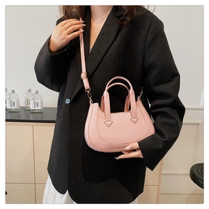 Detail of adjustable leather strap and reinforced handle on pink crescent bag