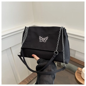 Close-up of black canvas shoulder bag with silver butterfly embroidery and chain strap