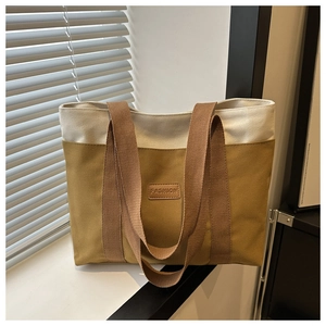 Détail du sac cabas en toile bicolore avec étiquette en cuir marron 'FASHION' chic