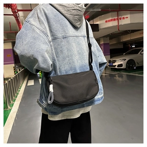 Vue détaillée du sac bandoulière noir en forme de croissant avec nœud latéral décoratif