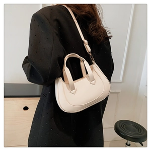 Close-up of a minimalist cream crescent bag with double handles and adjustable strap