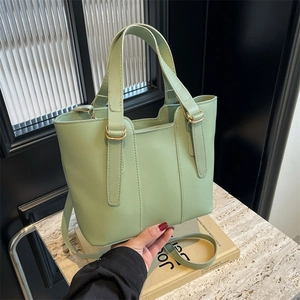 Elegante borsa a secchiello verde chiaro con finiture dorate e tracolla in un set moderno