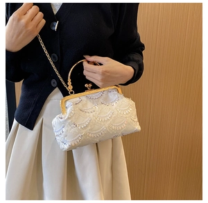 Close-up of white lace evening bag with sequins and gold metal ring handle detail
