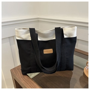 Détail de l'écusson en cuir avec texte FASHION sur un grand sac cabas en toile bicolore